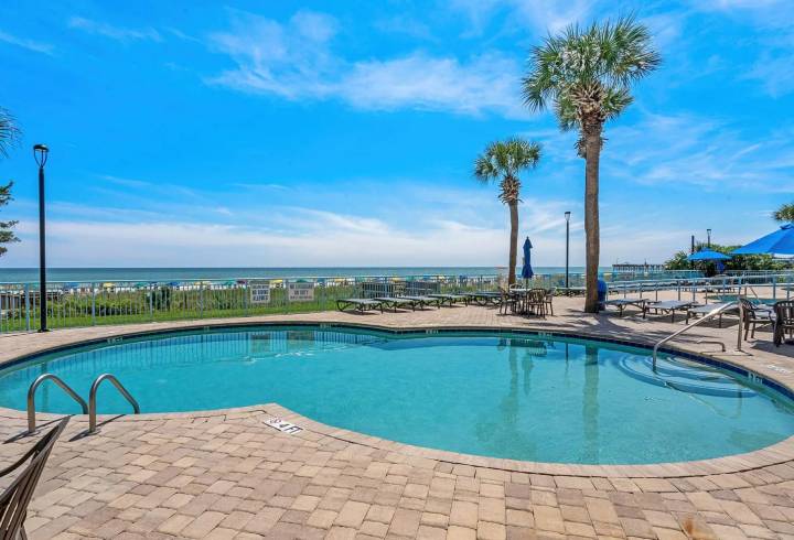 Outdoor pool with ocean view and palm trees.