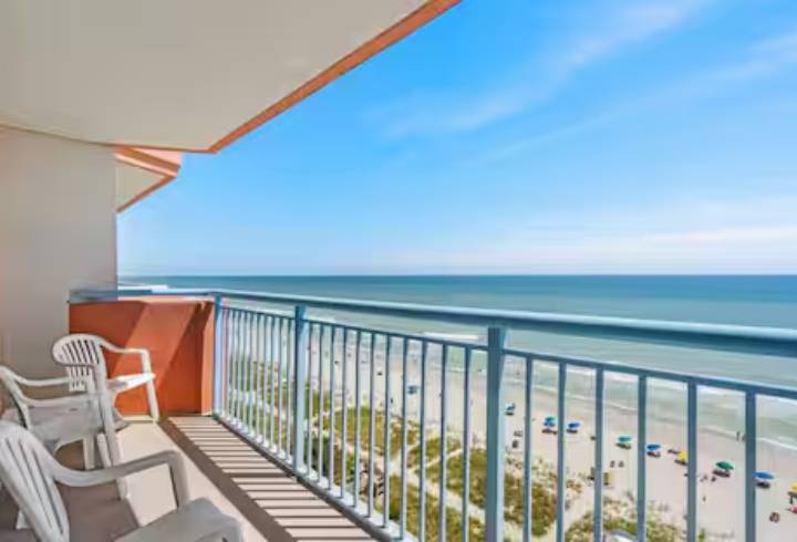 Beachfront balcony with ocean view and chairs.