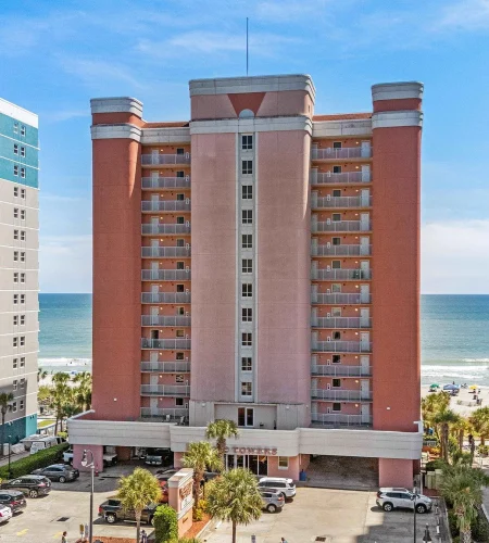 Beachfront hotel with ocean view and palm trees.