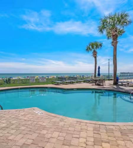 Outdoor pool with ocean view and palm trees.