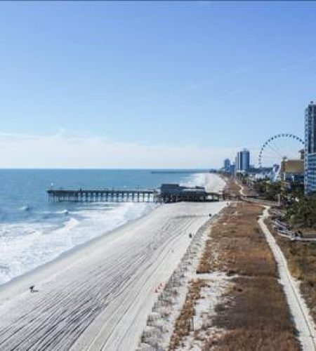 Coastal cityscape with beach and Ferris wheel.