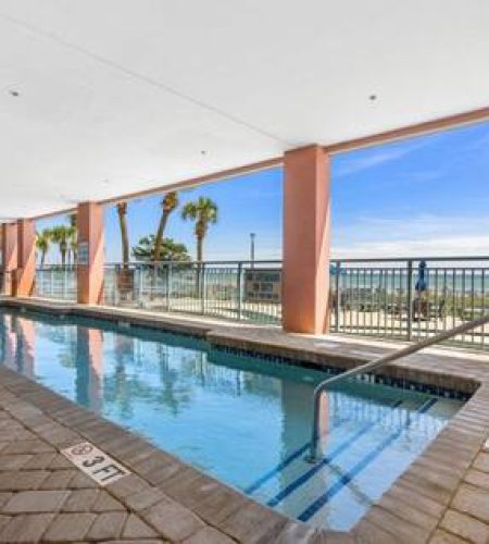 Indoor pool with ocean view and palm trees.