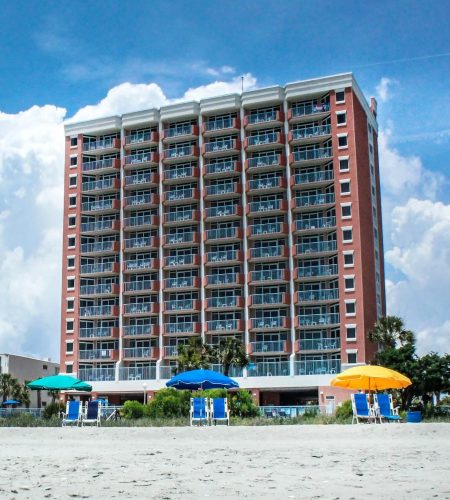 Beachfront hotel with colorful umbrellas and chairs.